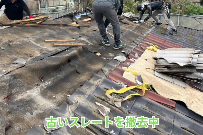 劣化したスレート屋根を数名の職人が丁寧に撤去している様子。