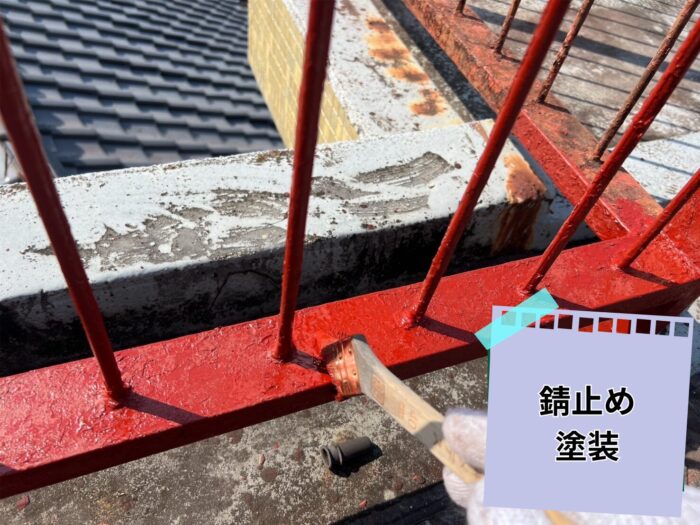 赤錆色の錆止め塗料をハケで丁寧に塗っている作業風景