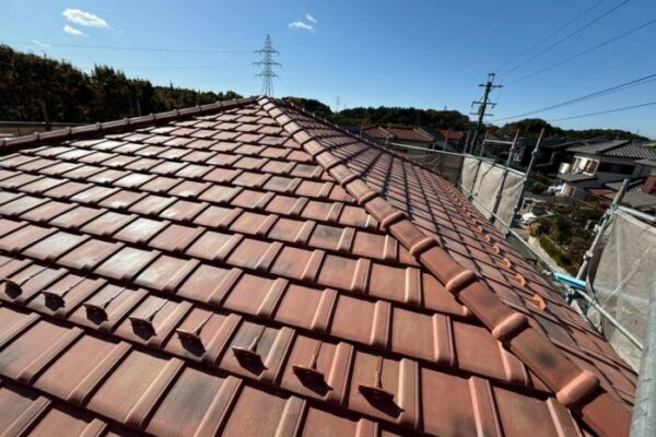赤系の瓦屋根が広がり、棟瓦が一直線に並んでいる。
