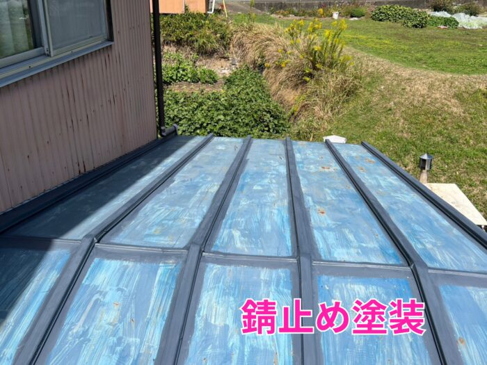 金属屋根全体に青みがかったサビ止め塗料が塗られ、リブ部分だけ濃い色でダメ込み処理されている施工途中の写真。