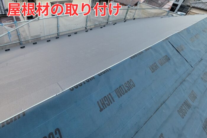 ガルバリウム屋根材を順に張り進めている状況。雪止め金具も固定されている