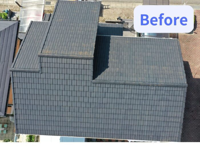 上空から撮影した住宅屋根の写真。葺き替え前の瓦屋根が全体的に映っており、色ムラや経年劣化の跡が見られる。建物の形状が複雑で複数の屋根面が組み合わさっている様子が分かる。