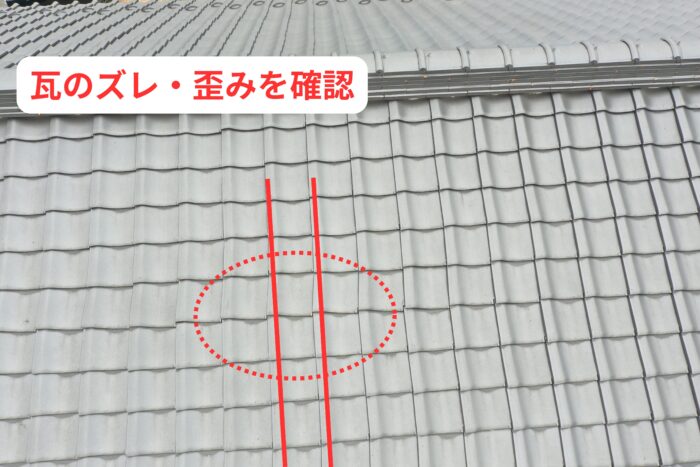 瓦のズレや歪みが発生している箇所を示している様子。棟付近から下方向にかけて瓦のラインが乱れている状態を確認している。