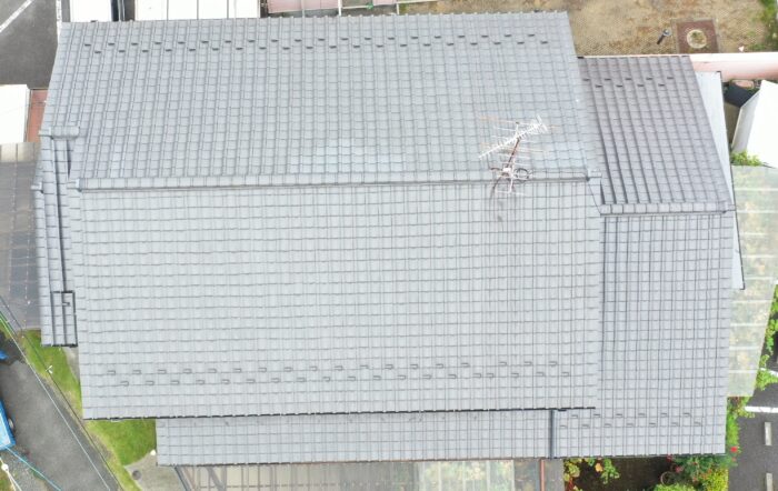 ドローンで真上から撮影した美濃加茂市田島町の瓦屋根全景。切妻屋根の棟や瓦の並びが確認でき、屋根全体の状態や劣化状況を点検している様子。