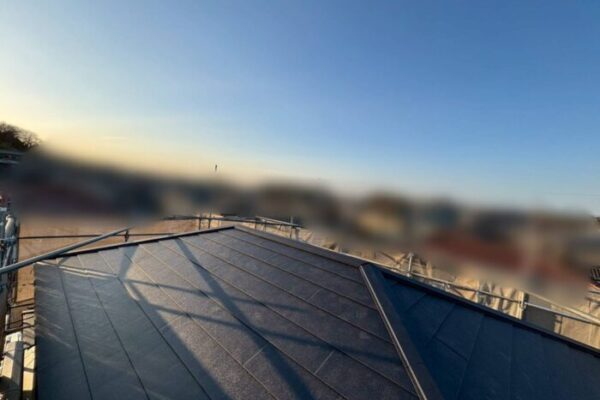 屋根工事後の金属屋根がきれいに仕上がり、均一に並んだ屋根材と棟部分が確認できる。