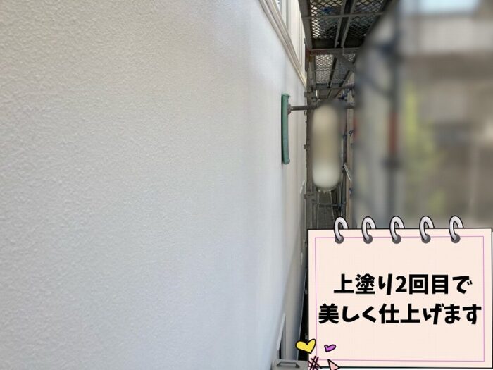 外壁に上塗り2回目の塗装を施工している様子