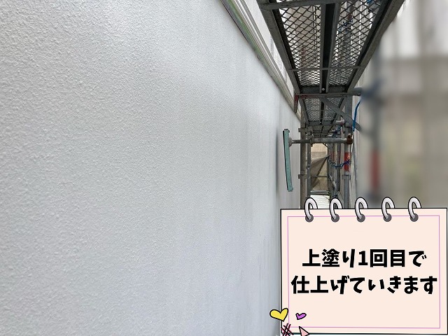 外壁に上塗り1回目の塗装を施工している様子
